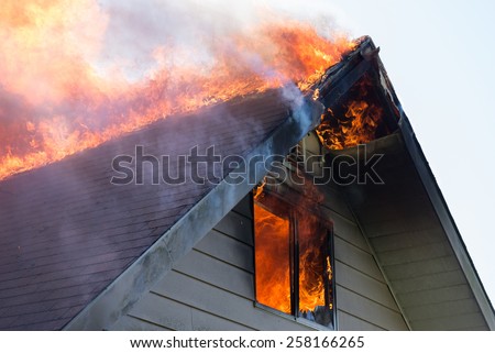 Close view of flames in an upper story window and running across the roof ridge.