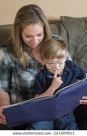 A mother and son enjoy quality time as she reads a book to him.