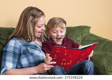 A young child gets ready to read by singing with his mother using a book based on a song.