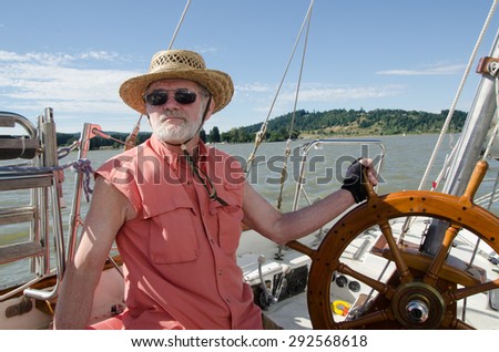 A senior man at the helm of sailboat navigates on Fern Ridge Reservoir near Eugene, Oregon.
