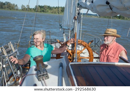 A happy senior couple enjoys time together sailing on a lake on a fine summer day.