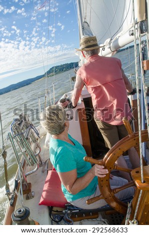 A ketch under full sail lists to starboard as the wind catches the sail on an Oregon lake.