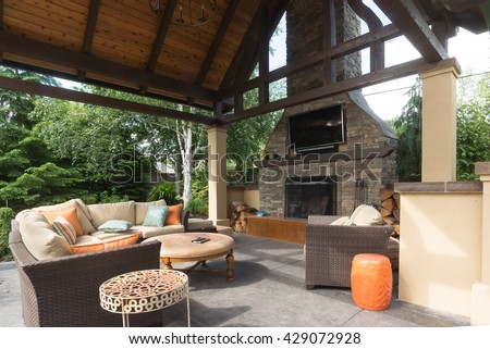 An upscale backyard terrace featuring perennials and with a custom designed shelter and fireplace.