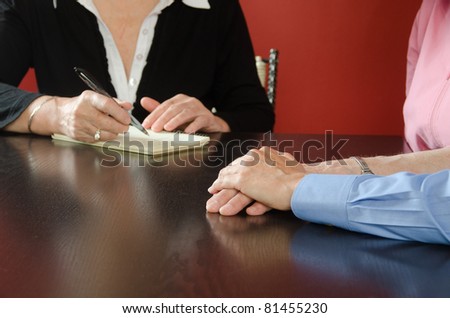 Close-up of therapist’s hands taking notes and two female hands.