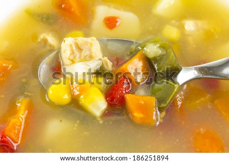 fresh chicken vegetable soup spoonful with carrots, corn, and tomato