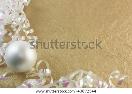 pearl white Christmas ornament with curly metallic ribbon on a textured gold background