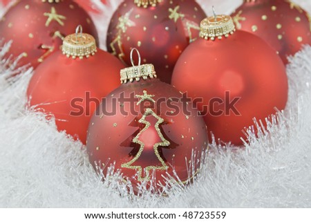 closeup of red Christmas bauble with gold glitter tree shape on pearl white garland