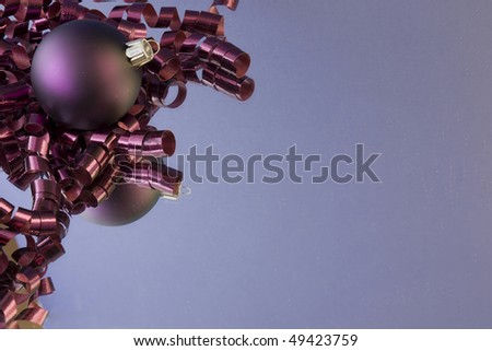 dark purple curly ribbon with purple christmas bauble and soft purple background