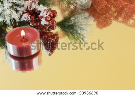 single red tealight candle with snow draped fir branch and red berries with copyspace