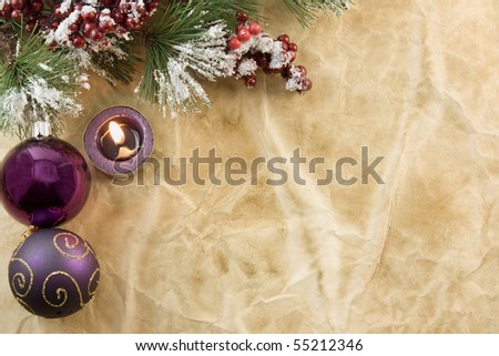 Christmas fir branch with purple tea light candle, baubles on antique paper with copyspace