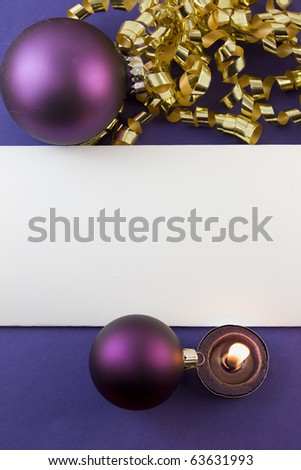 blank Christmas card with purple baubles, gold curly ribbon, tea light candle and copyspace