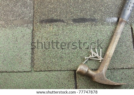 row of textured green asphalt shingles with hammer and roofing nails