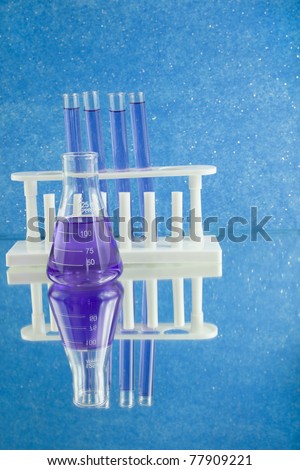 lab glassware flask and test tubes in rack filled with blue liquid as a medical research concept with reflections