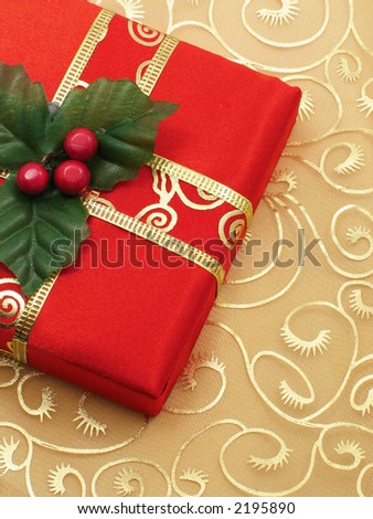 Red Christmas gift box with gold ribbon on gold silk background.