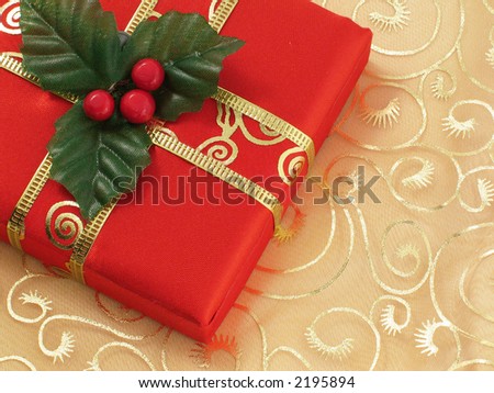 Red Christmas gift box with gold ribbon on gold silk background.