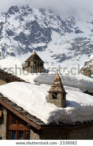Snow roofs and chimneys on a background of mountains