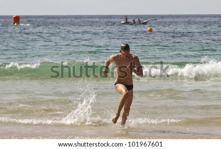MOLLYMOOK, NSW, AUSTRALIA - APRIL 15 - Brad Horrey winner of the Mollymook Beach Ocean Swim running towards the finish line on the 15th of April 2012.
