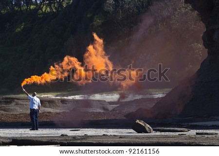 ULLADULLA, AUSTRALIA - CIRCA DEC. 2011:Policeman holds up smoke flare to signal NSW ambulance helicopter at Racecourse beach on December 24, 2011.
