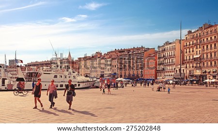 MARSEILLE - JULY 2, 2014: Old port (Vieux-Port) with people walking along the promenade and basilica of Notre-Dame-de-la-Garde on July 2, 2014, Marseille.