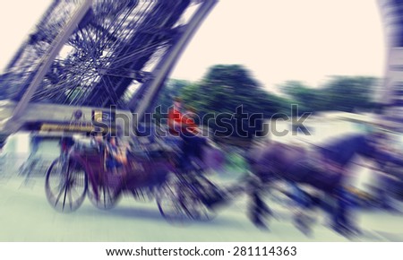 Abstract background. Paris, tourists in carriage with horses near the Eiffel Tower. Defocusing filter applied, with vintage instagram look.