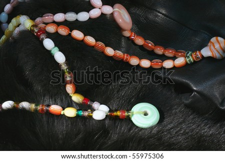 Woman necklaces made of semi-precious stones on black fur as a background