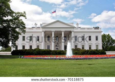 The White House in Washington DC in spring with fountain and red tulips.