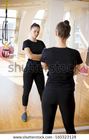 Fitness girl looking herself in a mirror