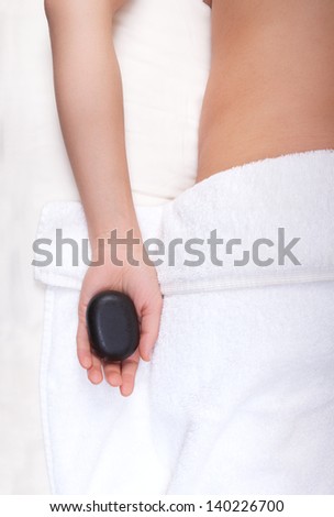Relaxed woman with a hot stone in her hand in a spa salon