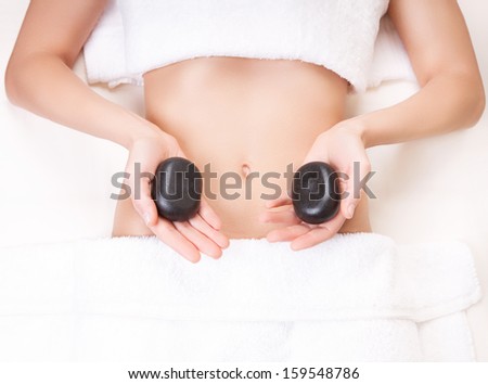 Relaxed woman with a hot stone in her hands in a spa salon