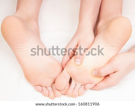 Therapist doing a foot massage,  pressing reflexology zones on the woman\'s right foot