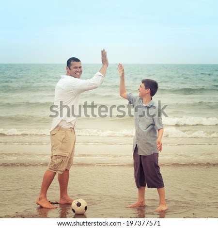 Happy father and son high-fiving on the beach
