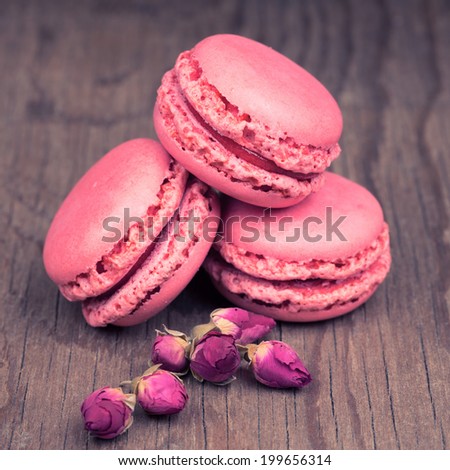 Macaroons with dry roses on retro vintage wooden background