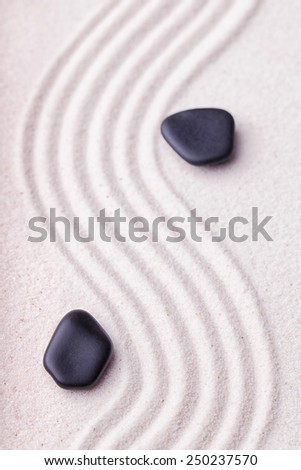 Zen garden with a wave lines in the sand with relaxing black stones