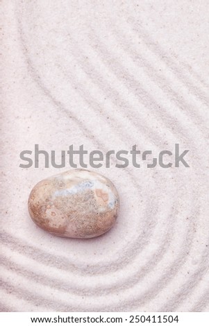 A marble rock  and wave pattern in the sand of a zen garden