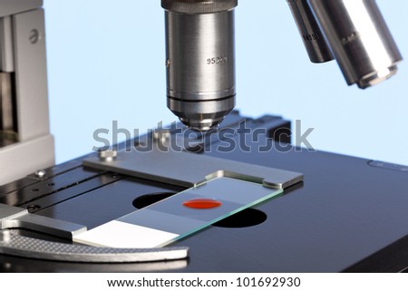 Photo of a laboratory microscope with a blood sample on a glass slide.