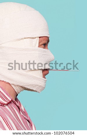 Photo of a Hospital patient with a bandaged head and a thermometer in his mouth having his temperature taken.