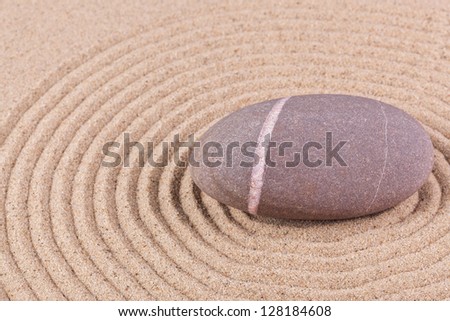A single pebble in a raked sand circle zen garden.