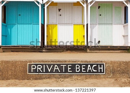 Old wooden beach huts on a Private beach with sign