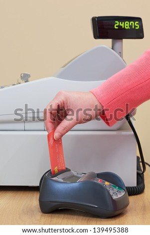 A woman putting her credit card into the card machine in a shop.