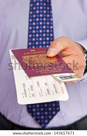 Close-up of a businessman handing over his boarding pass and passport at airport check-in. The tickets are mock ups and all details and names are generic.