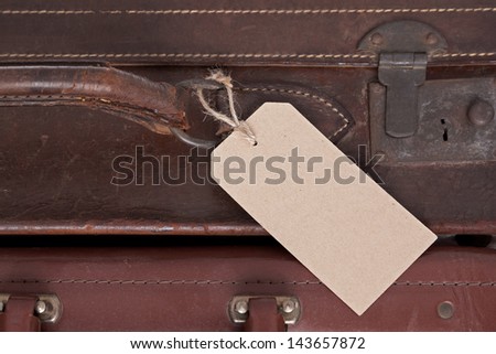Photo of a blank baggage label on an old brown leather suitcase.