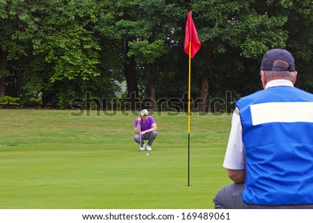 A professional golfer and his caddy reading the green to judge the line of the putt. Series of three photos.