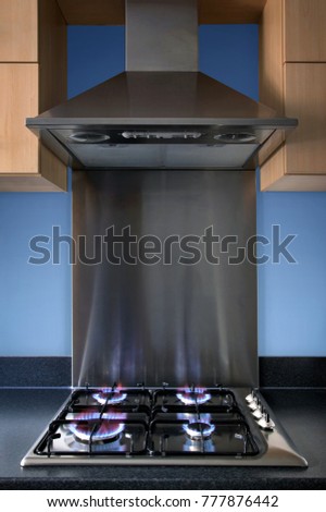 Modern steel kitchen gas hob and extractor hood.