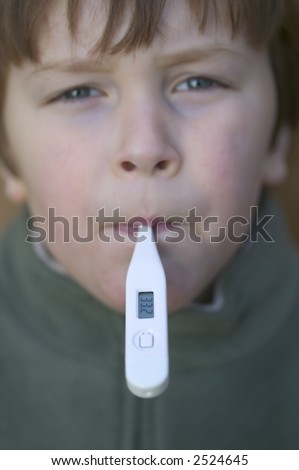Young boy having his temperature taken with a digital thermometer, focus on the read out