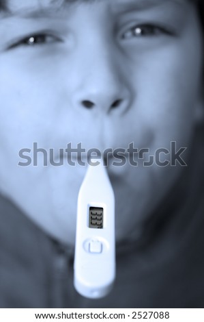 Young boy digital thermometer in his mouth,focus on the read out,toned blue to emphasise \'cold\'