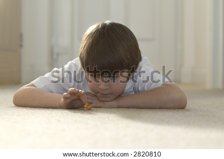 Boy playing marbles at home lying on a carpet