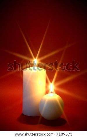 Two white candles burning against a red background, Christmas theme.