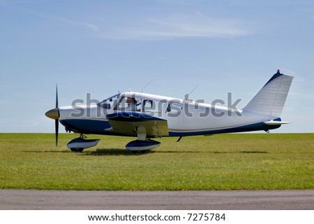 Light aircraft taxiing on a grass runway about to take off.