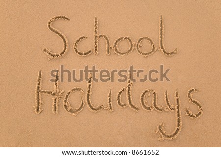 School Holidays handwritten in sand.