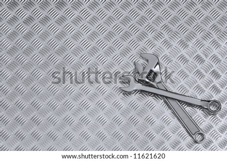 Mechanical background image of two spanners on a checkerplate workbench.